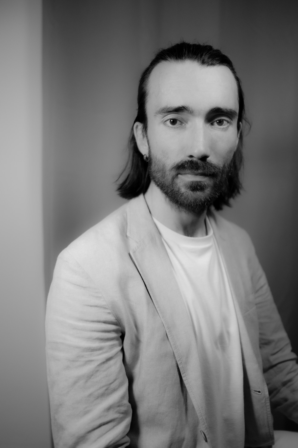 Black and white studio portrait of a man in a linen jacket